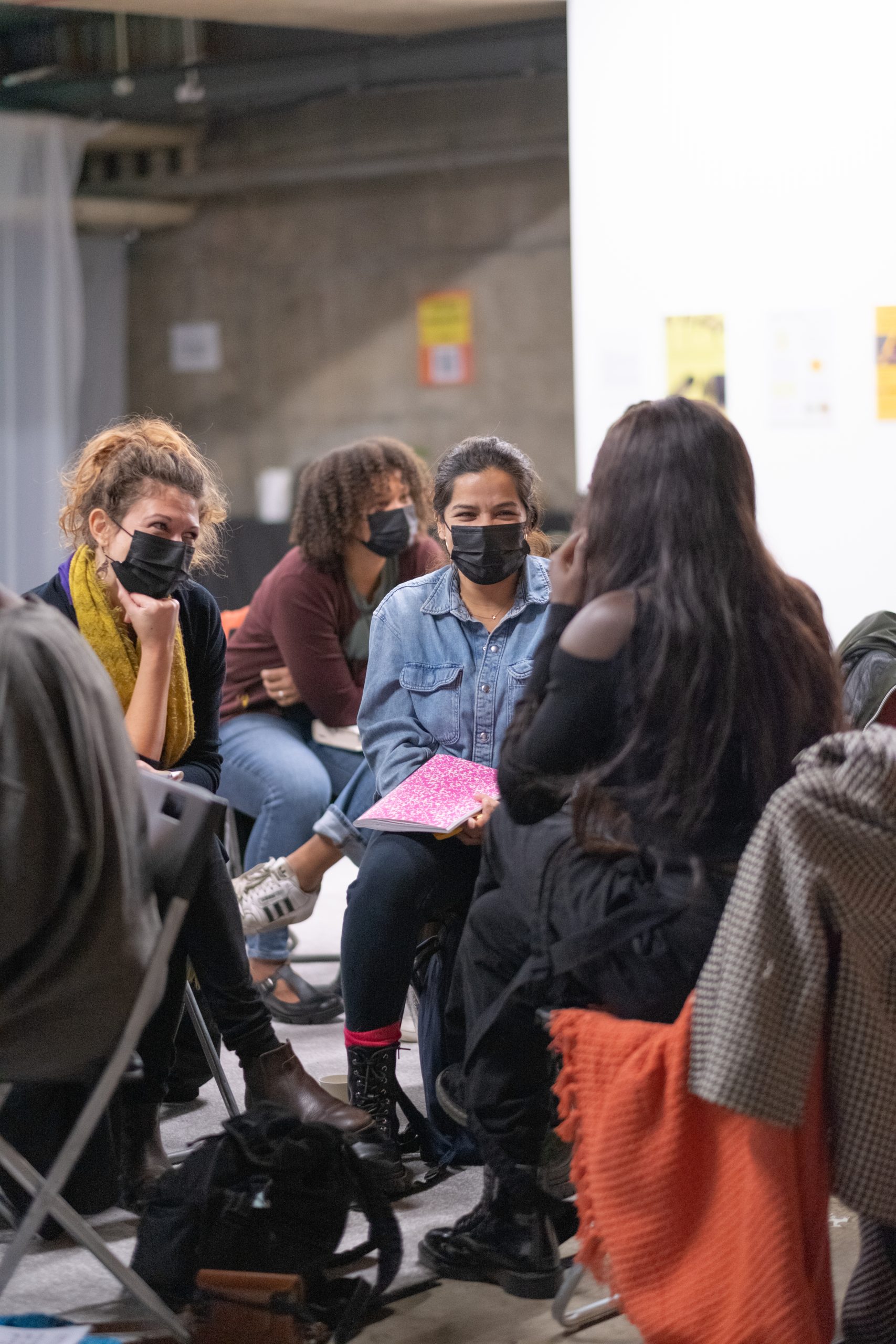 A diverse group of people in discussion, sitting down, wearing face masks.