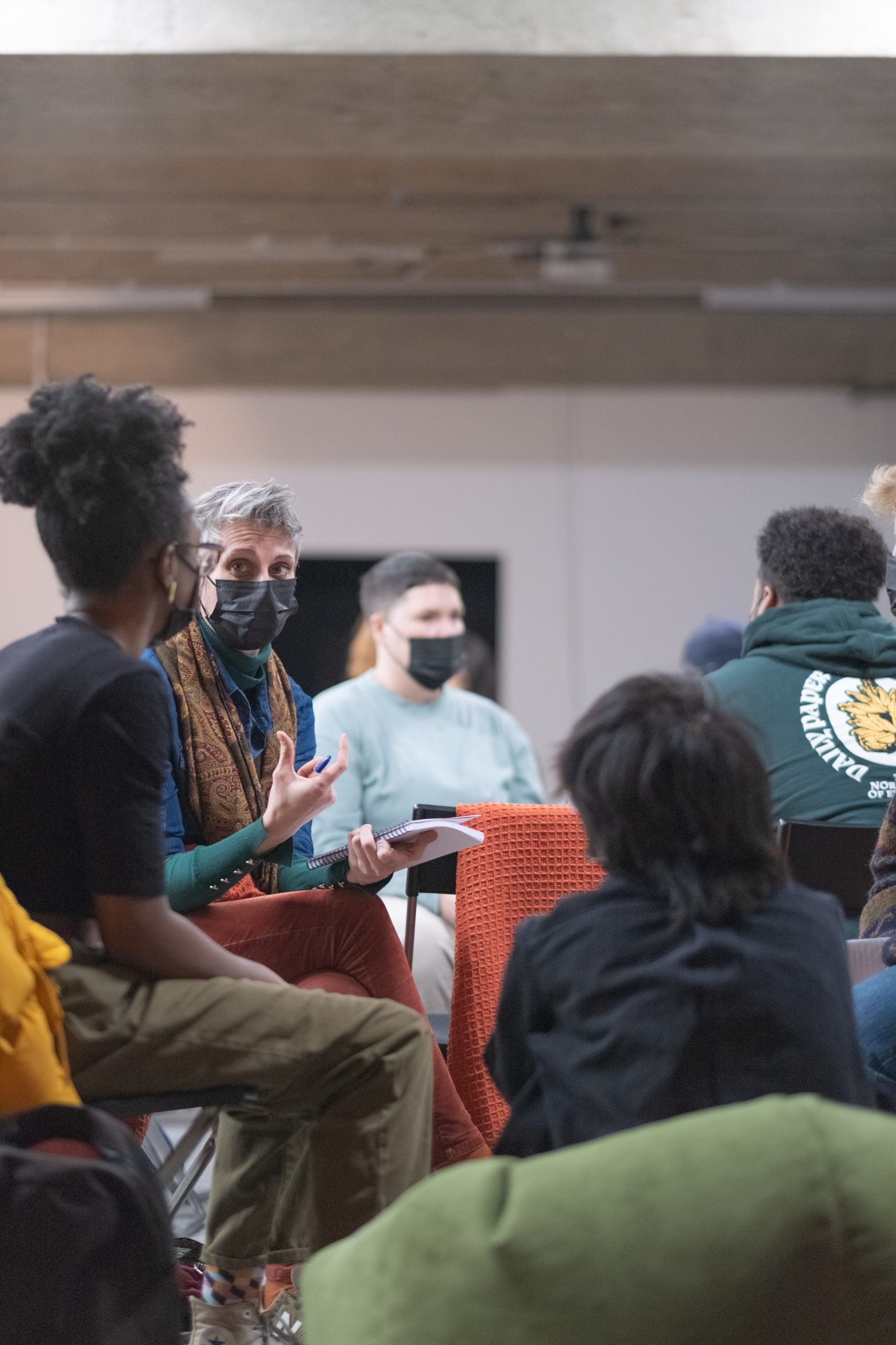 A diverse group of people in discussion, sitting down, wearing face masks.